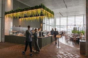 Een moderne binnenruimte met een bar, zitplaatsen en grote ramen.