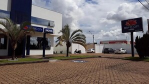 A hotel with a paved entrance, palm trees, and a clear sky. - Bravo City Hotel Primavera do Leste (Primavera do Leste)