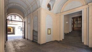 Eine prachtvolle Eingangshalle mit Marmorboden, gewölbten Decken und einer Treppe, die in einen zweiten Stock führt.