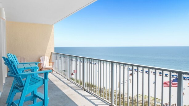Un balcon avec des chaises bleues et vue sur la plage.