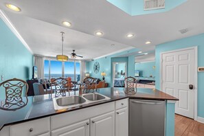 A modern kitchen with a central island, white cabinetry, and a view to the outside. - San Carlos 707 (Gulf Shores)