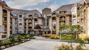 A multi-story hotel with balconies, a central courtyard, and a small building with a sloped roof. - The Mountain View Condo - Large 2BR/2BA (Whistler)