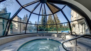 An indoor swimming pool with a glass dome ceiling, surrounded by tiled flooring and metal railings. - The Mountain View Condo - Large 2BR/2BA (Whistler)