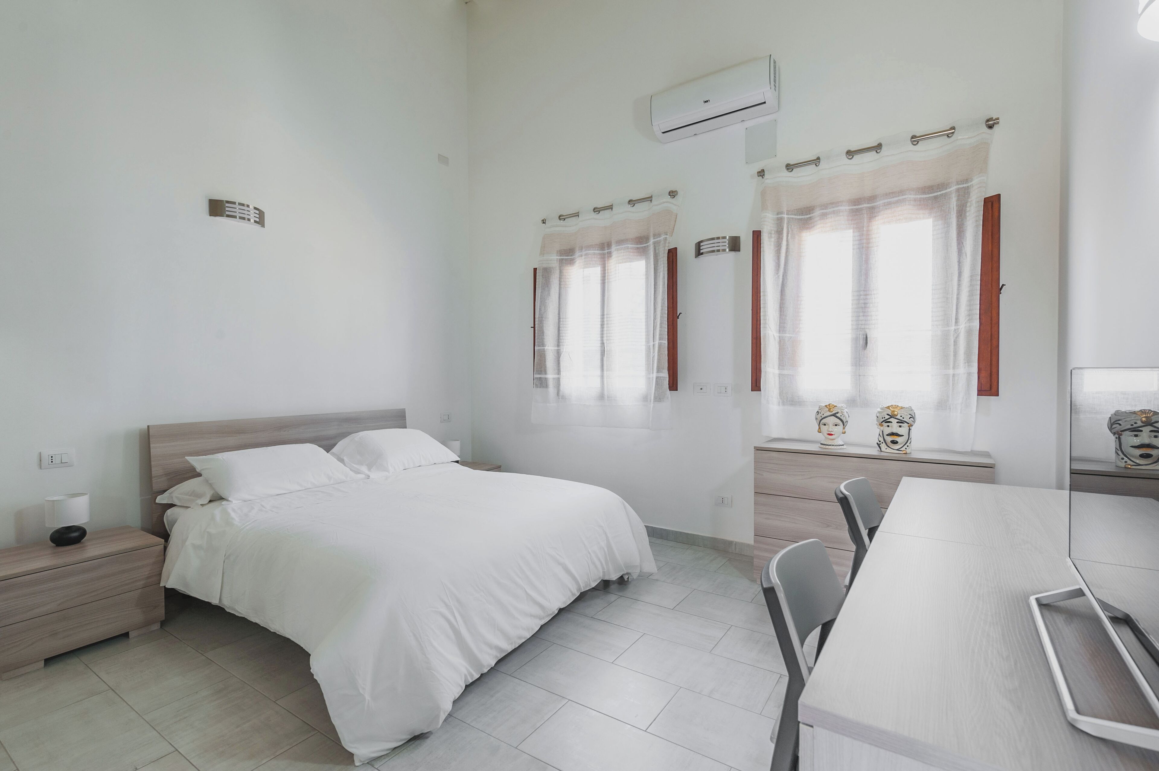 Una camera d'albergo con un letto, un comodino e un tavolino con sedie.