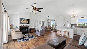 A spacious living area with a fireplace, a ceiling fan, and a kitchen with a large island. - The Extra Mile, One Level, 2BR, Great for couples or small families! (Saint George Island)
