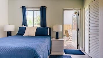 Une chambre à coucher avec un lit, deux tables de chevet avec des lampes, une fenêtre avec des rideaux et une vue sur l’extérieur.