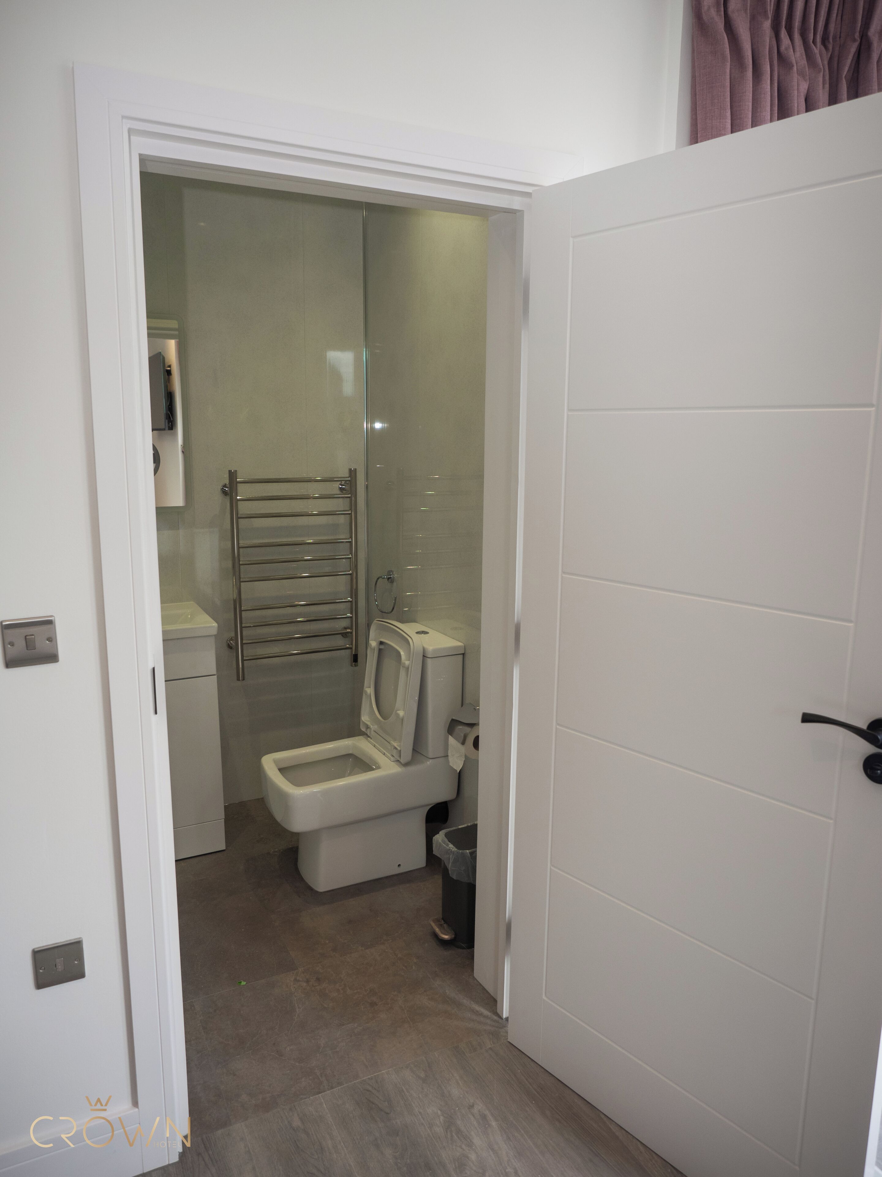 Un baño pequeño y moderno con inodoro, cabina de ducha de vidrio y un perchero para toallas.