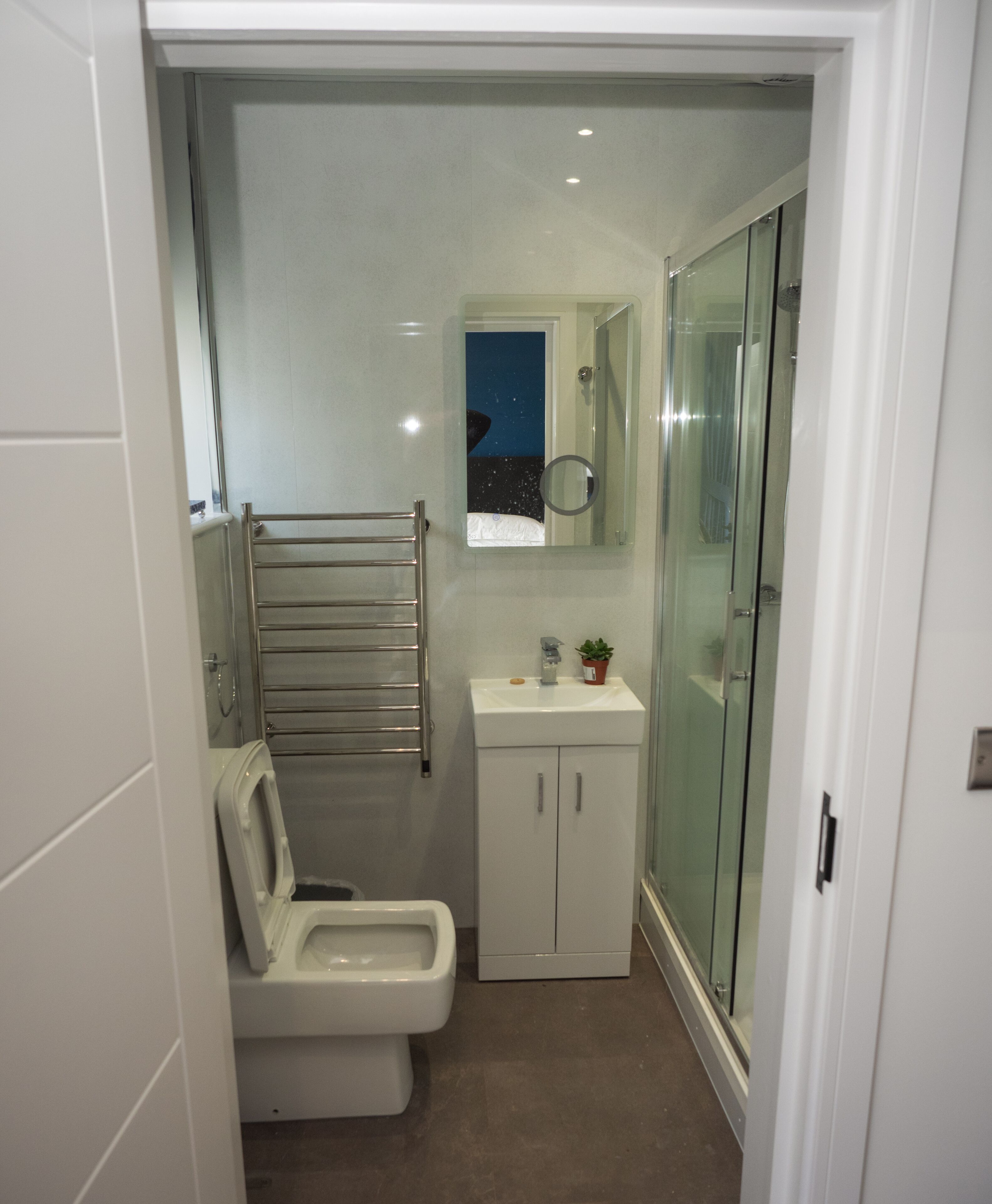 A compact bathroom with a toilet, a sink, and a glass shower enclosure.