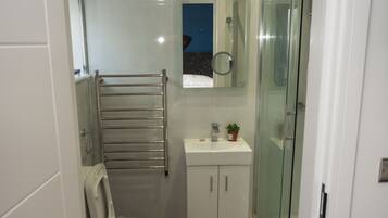A compact bathroom with a toilet, a sink, and a glass shower enclosure.