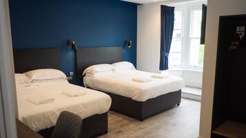 Ein Hotelzimmer mit zwei Betten, einem Schreibtisch und einem Fenster mit Vorhängen.