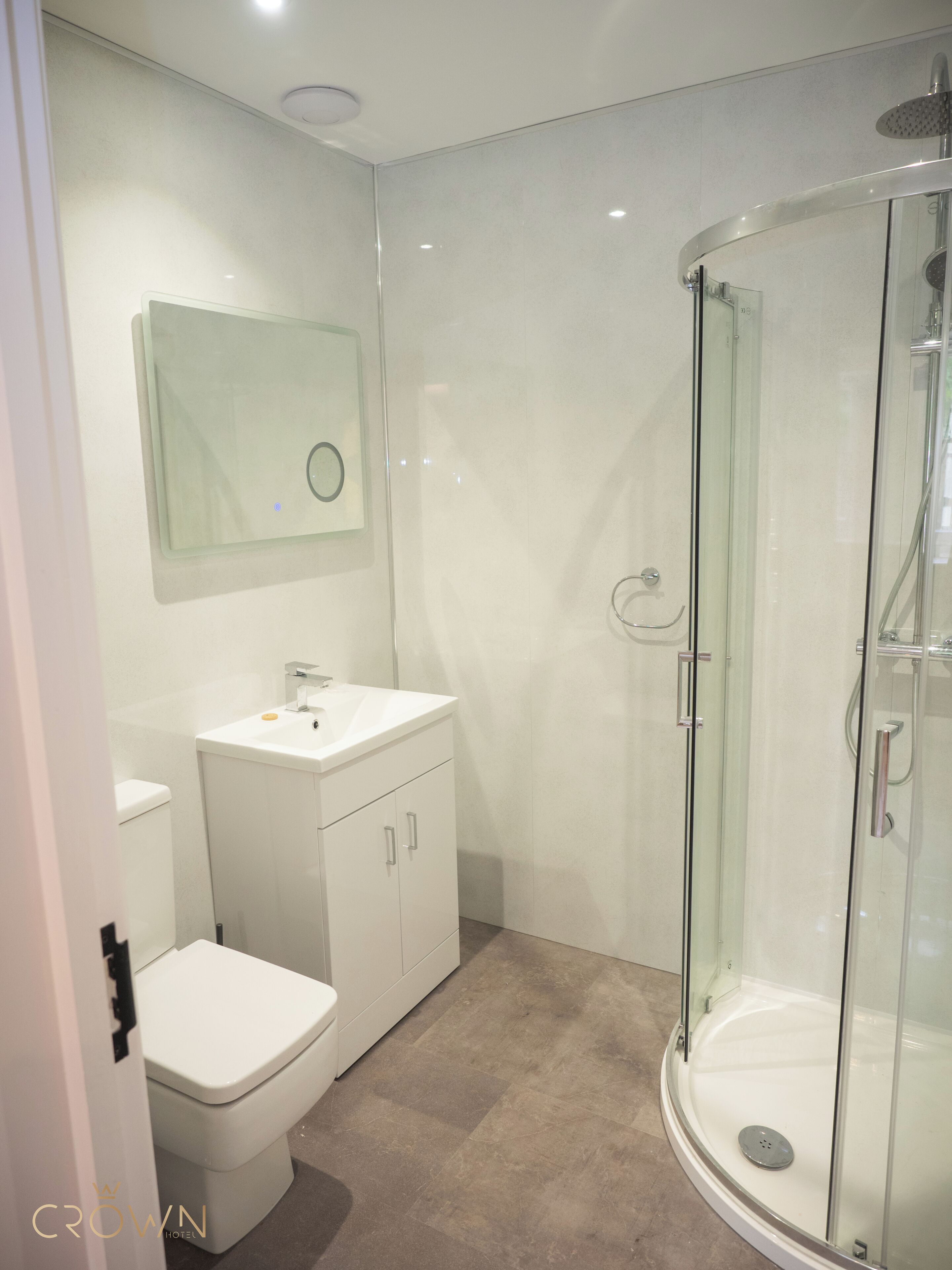 A modern bathroom with a glass-enclosed shower, a white sink, and a toilet.