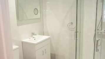 Un baño moderno con ducha acristalada, lavabo blanco y retrete.