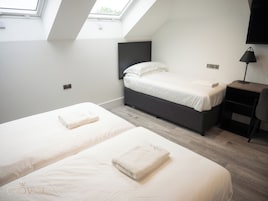 Un dormitorio moderno con dos camas, un escritorio y un televisor.