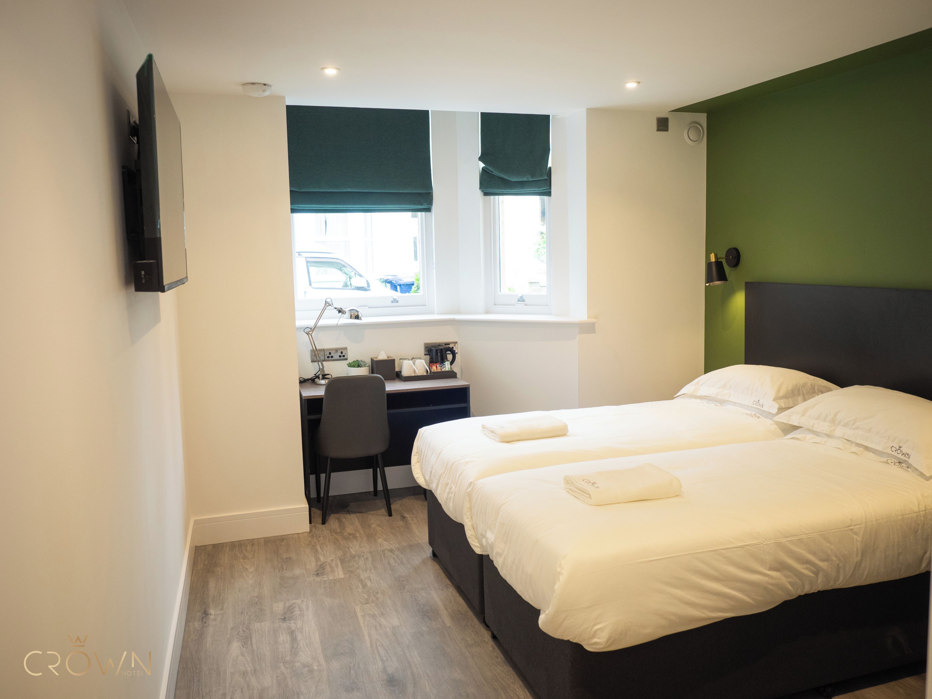 A hotel room with a bed, a desk, a chair, and a window with blinds.