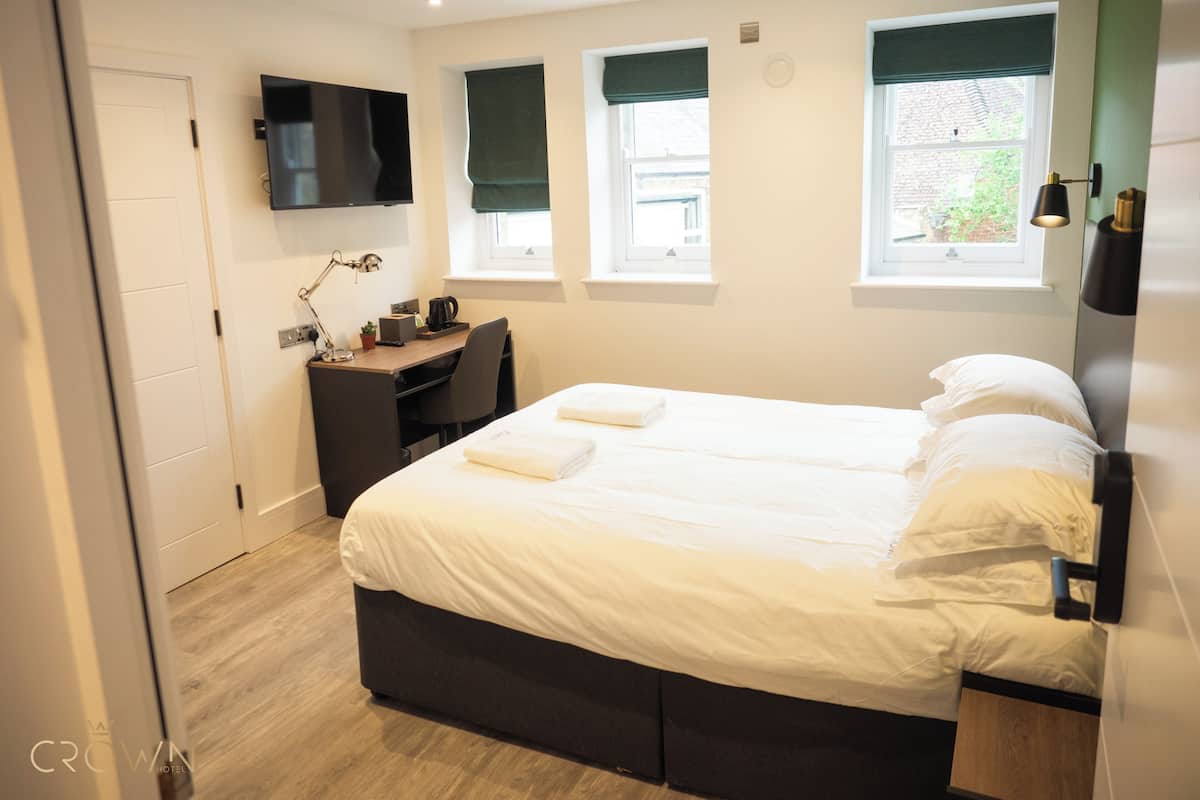 A hotel room with a bed, desk, and TV.