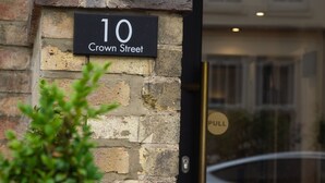 A black sign with white lettering indicating "10 Crown Street" on a stone wall. - Crown Hotel (Oxford)