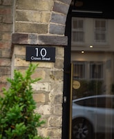 A black sign with white lettering indicating "10 Crown Street" on a stone wall.
