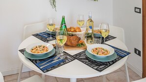Una mesa de comedor con platos de comida, vasos y botellas, rodeada de sillas.