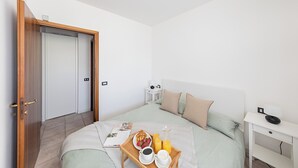 Un dormitorio con cama, mesita de noche y una bandeja con alimentos para el desayuno.