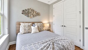 Un dormitorio con una cama grande, dos mesitas de noche, una lámpara de pared y una puerta doble.