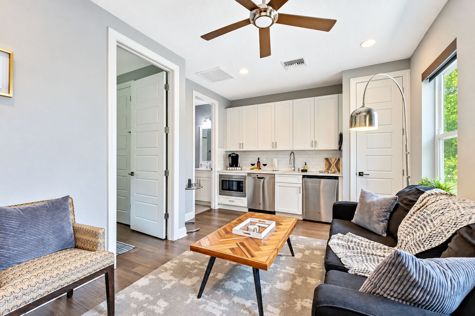 A modern kitchen with white cabinets, stainless steel appliances, and a dining area with a wooden table and chairs.