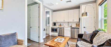 A modern kitchen with white cabinets, stainless steel appliances, and a dining area with a wooden table and chairs.