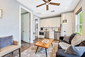 Una cocina moderna con armarios blancos, electrodomésticos de acero inoxidable y un comedor con mesa y sillas de madera.