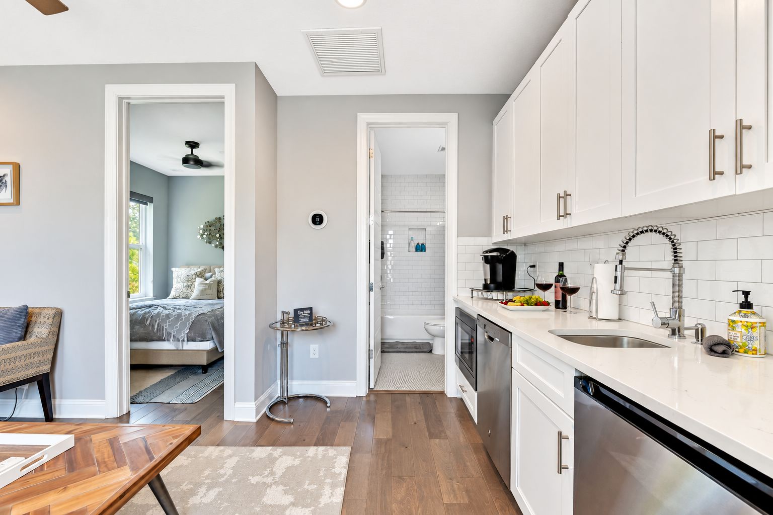 A modern kitchen with white cabinets, stainless steel appliances, and a breakfast bar.
