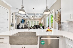 A modern kitchen with a large island, stainless steel appliances, and pendant lighting.