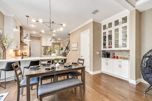 Una cocina moderna con zona de comedor, suelo de madera y muebles de cocina blancos.