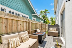 Une terrasse extérieure avec une plateforme en bois, un canapé, un foyer et une plante en pot.