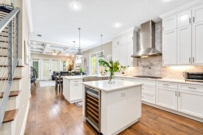 Une cuisine moderne avec des meubles blancs, un îlot central et un four encastré.