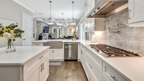 A modern kitchen with white cabinetry, stainless steel appliances, and pendant lighting.