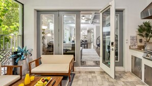 A modern kitchen with a dining area, a sofa, and a coffee table with fruit.