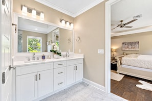 A bathroom with a double sink vanity, a large mirror, and a ceiling fan.