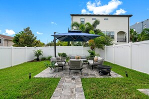 Un patio trasero con zona de estar, una chimenea y una pérgola.