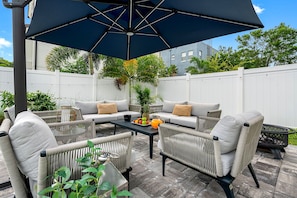 An outdoor patio with a sofa set, a table with fruit, and a large umbrella.