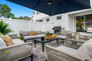 An outdoor patio with wicker furniture, a grill, and a table with fruit.