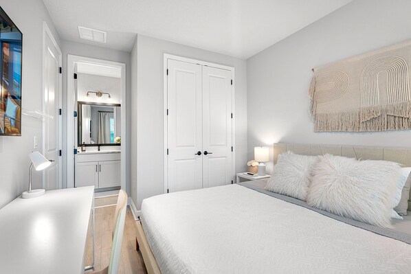 Un dormitorio con cama, mesita de noche, lámpara y un espejo grande.
