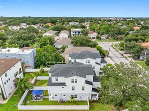 Un quartier résidentiel composé de plusieurs maisons à deux étages, avec un ciel dégagé et une rue bordée de voitures garées.