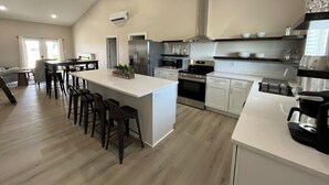 A modern kitchen with a central island, stainless steel appliances, and a dining area with bar stools.