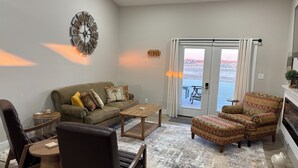 A living room with a sofa, armchairs, a coffee table, and a patterned rug.