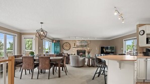 A spacious living area with a fireplace, dining table, and comfortable seating. - Mountain Manor | Lake Views & Access | Fenced Yard (Invermere)