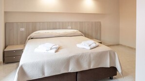 A neatly made bed with a headboard, two bedside tables, and an air conditioning unit above. - Sant'Janni - Buonalbergo (Buonalbergo)