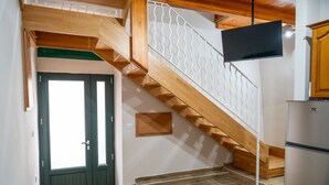 A staircase with wooden steps and a metal railing, a door with a green frame, and a kitchen area with a refrigerator. - Sant'Janni - Buonalbergo (Buonalbergo)