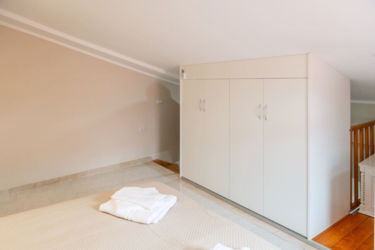 A room with a large wardrobe, a small table, and a folded white towel on the floor.