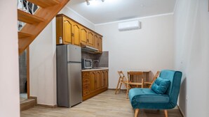 A compact kitchen with wooden cabinets, a refrigerator, a microwave, and a small dining table with a chair. - Sant'Janni - Buonalbergo (Buonalbergo)