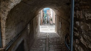 A stone archway leading to a cobblestone street with buildings in the background. - Sant'Janni - Buonalbergo (Buonalbergo)