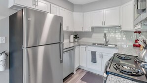 Une cuisine moderne avec des armoires blanches, des appareils en acier inoxydable et un dosseret carrelé.