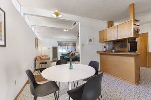 Un espace de vie compact comprenant un coin repas, une kitchenette et un canapé à l’arrière-plan.